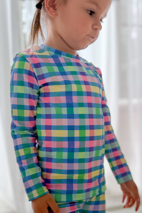 Child wearing a colorful plaid outfit with a white background